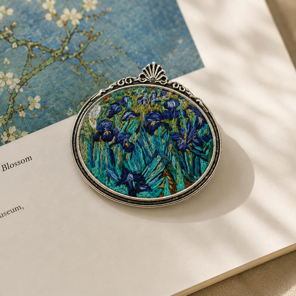 Hand-embroidered_brooch_inspired_by_Vincent_van_Gogh_s_Irises_displayed_on_an_open_art_book_in_soft_natural_light.