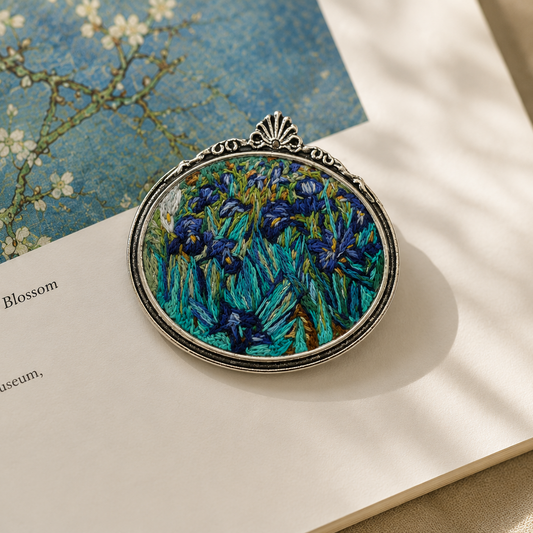 Hand-embroidered_brooch_inspired_by_Vincent_van_Gogh_s_Irises_displayed_on_an_open_art_book_in_soft_natural_light.
