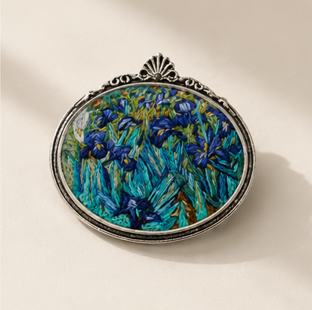 Handcrafted embroidered brooch inspired by Vincent van Gogh's Irises on a clean ivory background, showcasing intricate threadwork.