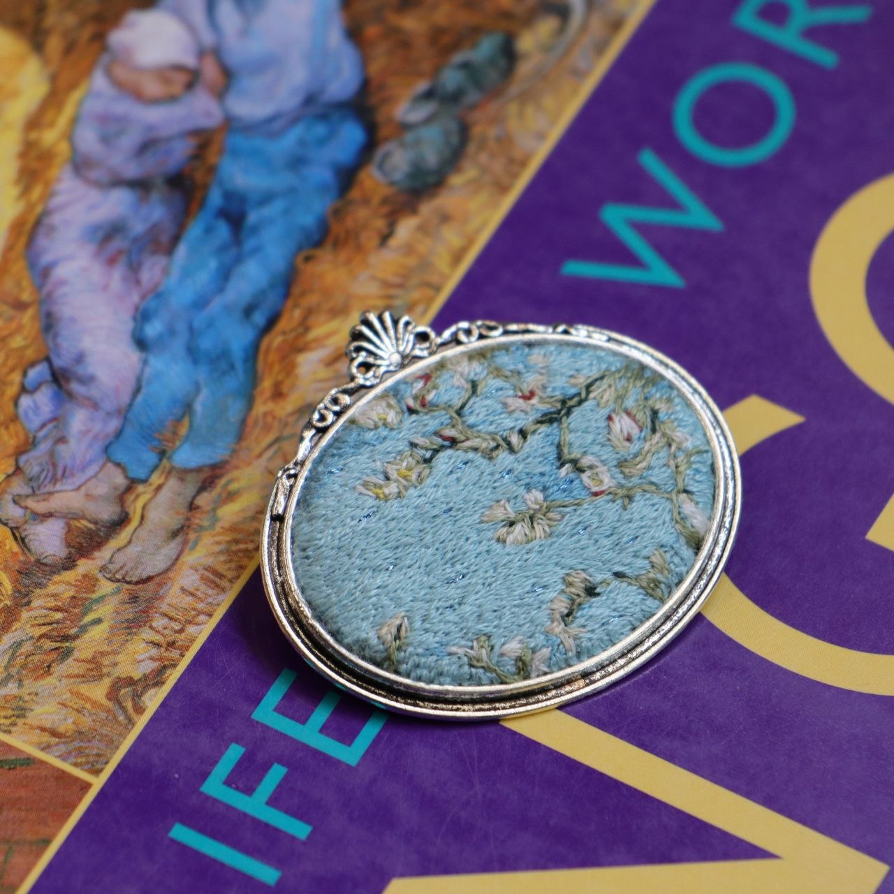 Hand embroidered brooch inspired by Vincent van Gogh's flowering branches, featuring white blossoms against a blue sky, handcrafted textile jewelry and wearable art by Mina.